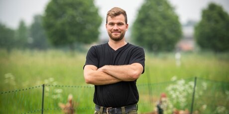 Nico steht vor dem Freigehege seiner Hühner.