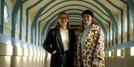 Johanna und Alina stehen in einem Gebäudegang.